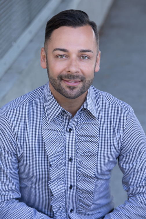 Photograph of Edgar Villanueva wearing a blue gingham shirt with ruffles down the buttons