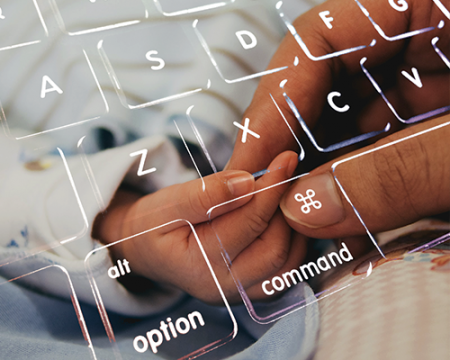 An image of an adult holding a baby's hand and a computer keyboard.