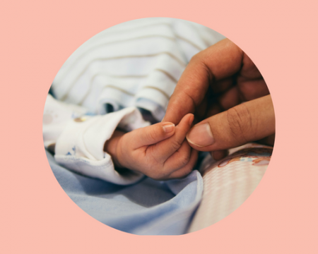 A light pink background with a circular photo of an adult hand holding an infant's hand 