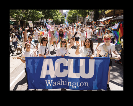 A group of staff and supporters holding an ACLU-WA Banner at the Pride Parade