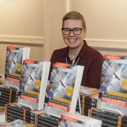 Third Place Books seller sitting behind a display of Decolonizing Wealth 