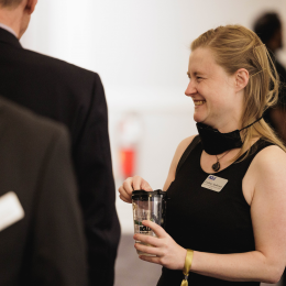 A person with blond hair holding a cup and smiling 