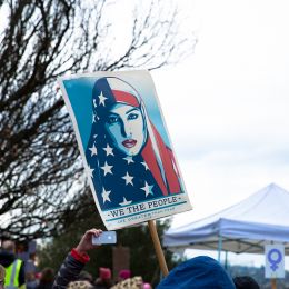 Photo of a sign picturing a Shepard Fairey illustration of a woman in an American flag hijab